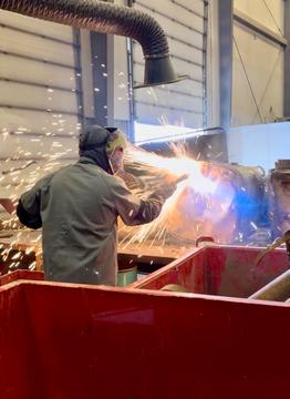Sell Scrap Metal | Worker Cutting Scrap Metal with Sparks in Recycling Facility